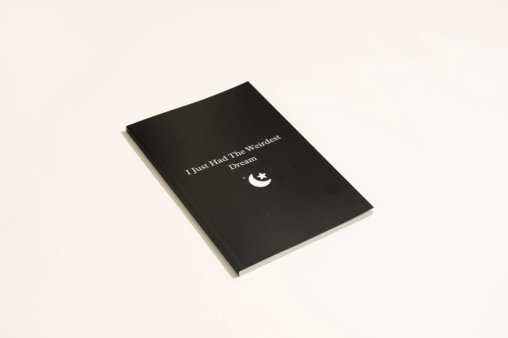 Black A5 hardback dream journal notebook open on a lined page and a dot grid page.