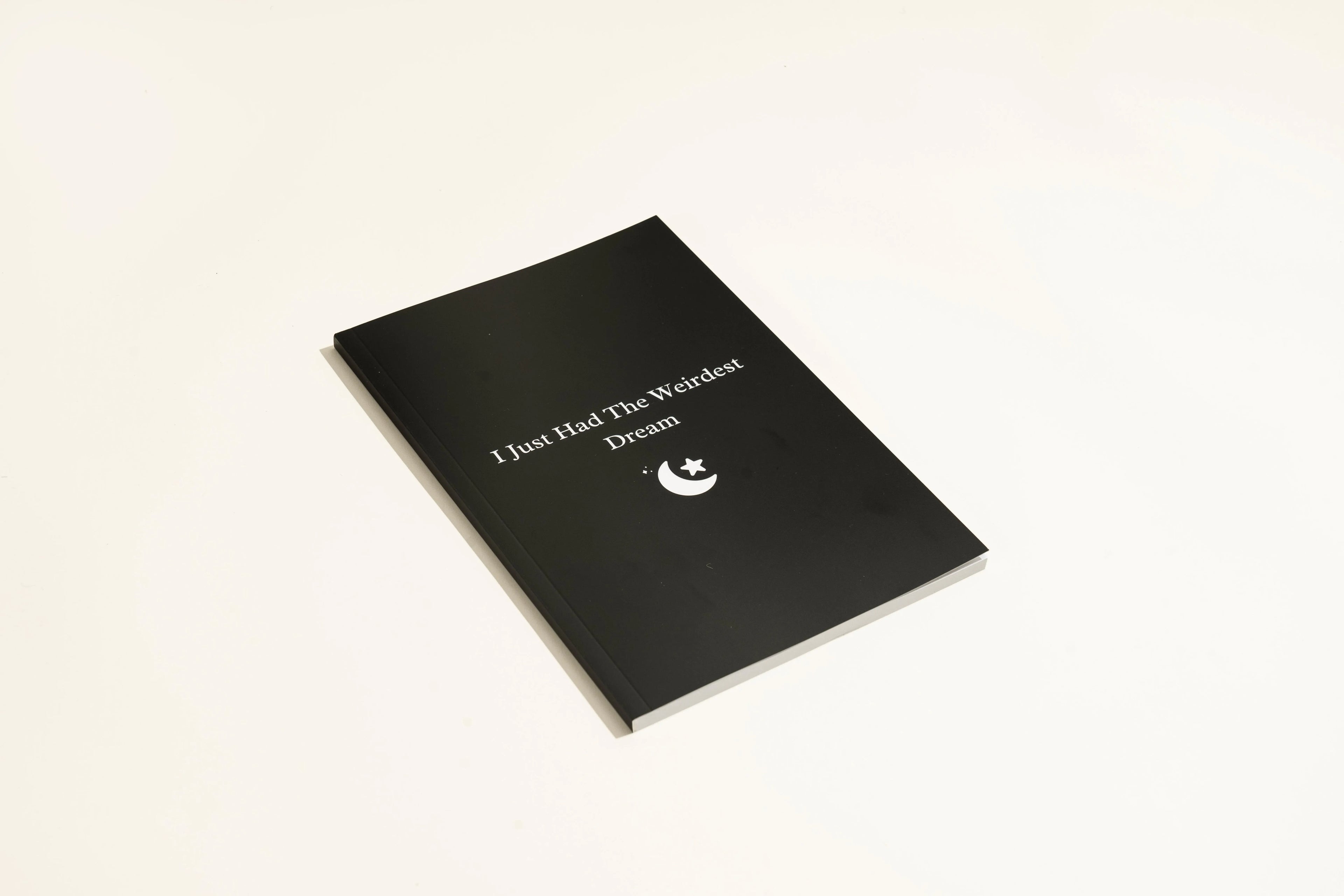Black A5 hardback dream journal notebook open on a lined page and a dot grid page.