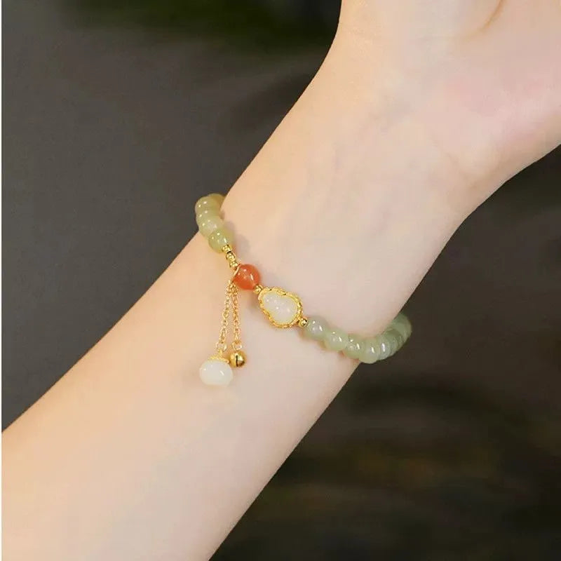 Jade women's bracelet with gold-plated fu character and a central gourd charm on wrist.