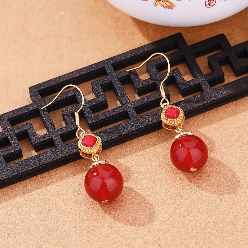Geometric drop earrings with red agate round beads and sterling silver inlaid jasper stones on a copper base.