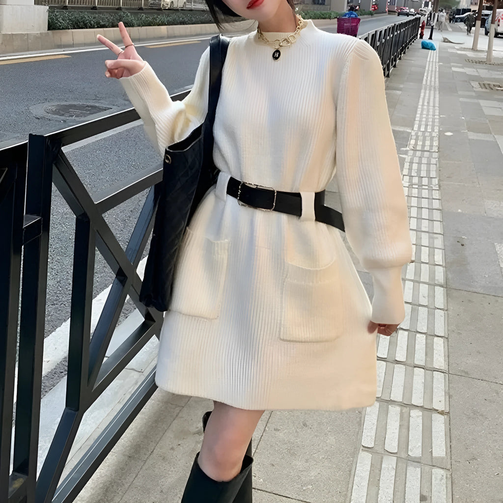 Long sleeve high-waist knitted dress on a hanger with a black belt, shown in beige colour.