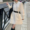 Long sleeve high-waist knitted dress on a hanger with a black belt, shown in beige colour.