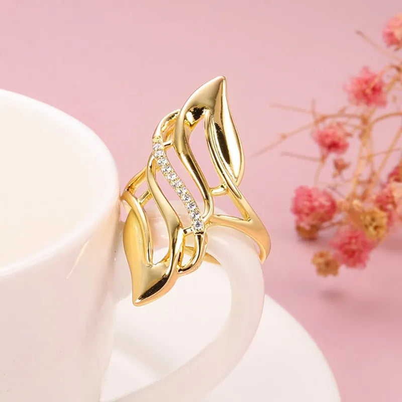 Gold-colour women's ring with exaggerated curved design and zircon crystal detail on a copper band.