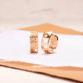 Rose gold hollowed out earrings with a three-heart design inside a circular shape.