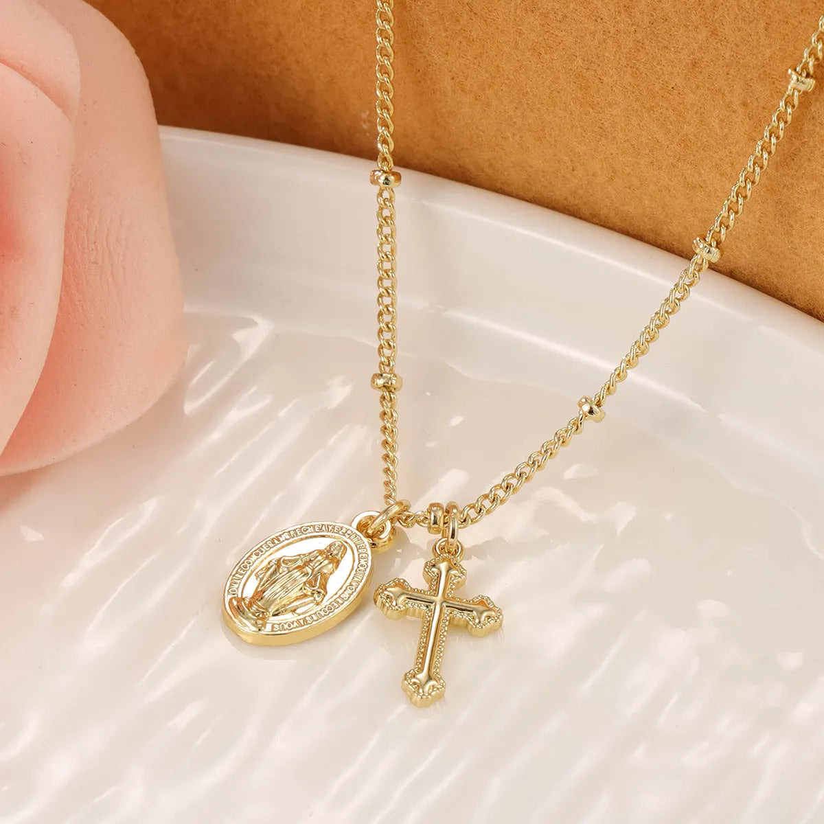 Gold geometric cross Virgin Mary pendant necklace on a chain.