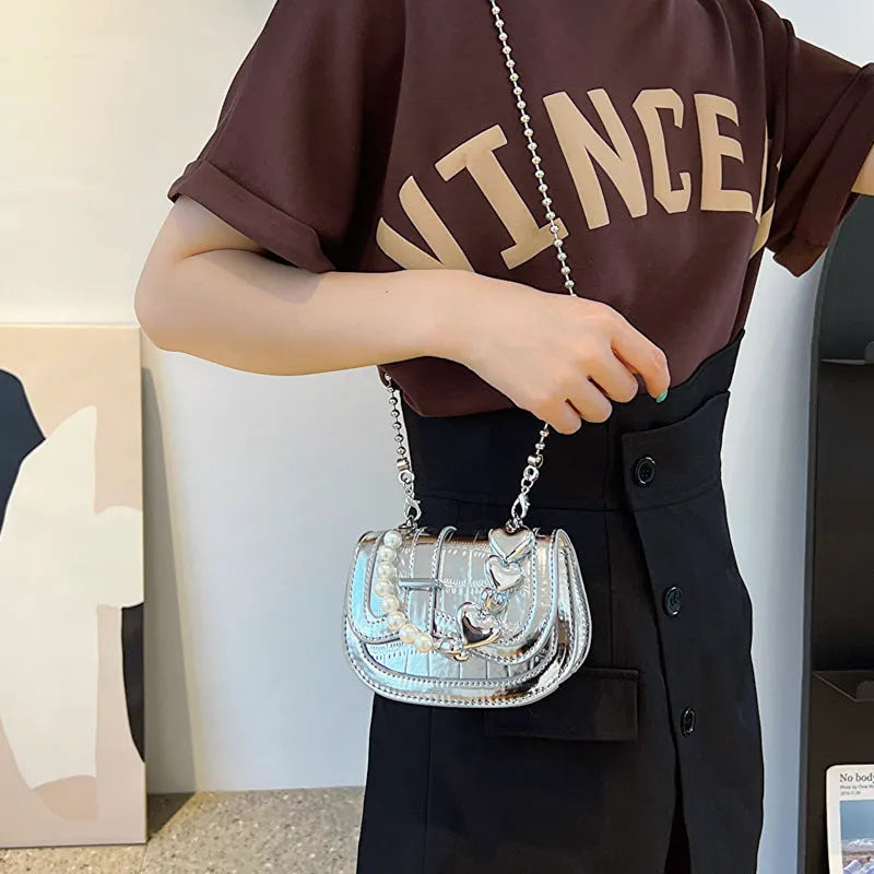 Laser pearl finish mini tote saddle crossbody bag in a choice of colours, shown with a single strap and structured square shape.