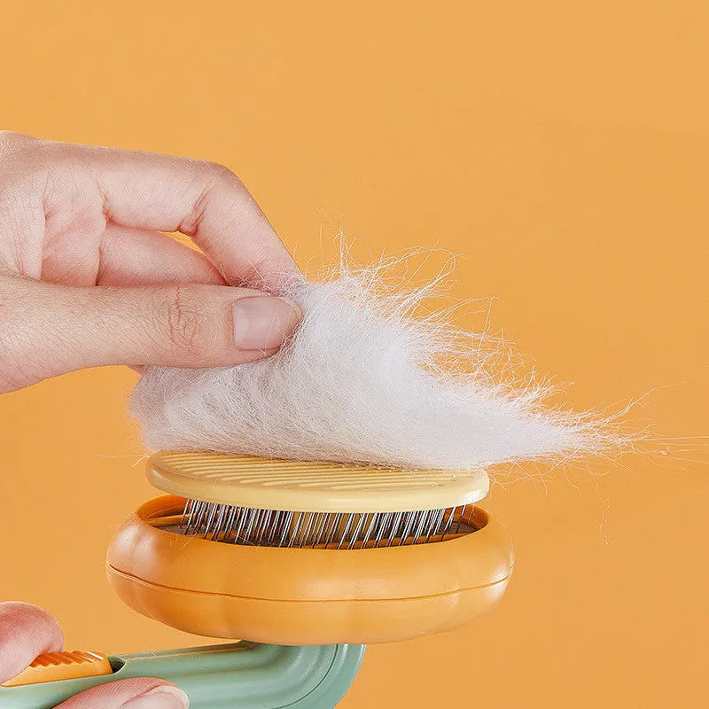 Hand holding a white and pumpkin coloured pet grooming brush with many stainless steel needles.