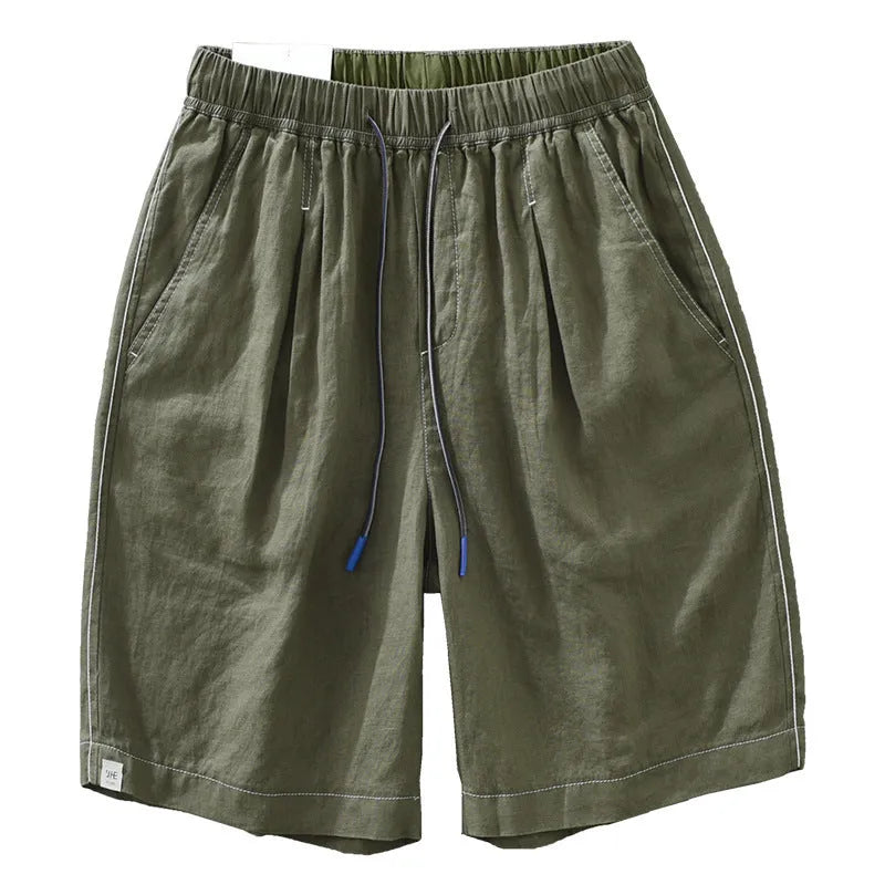 Man wearing green linen drooping shorts with a drawstring waist and mid-calf length.