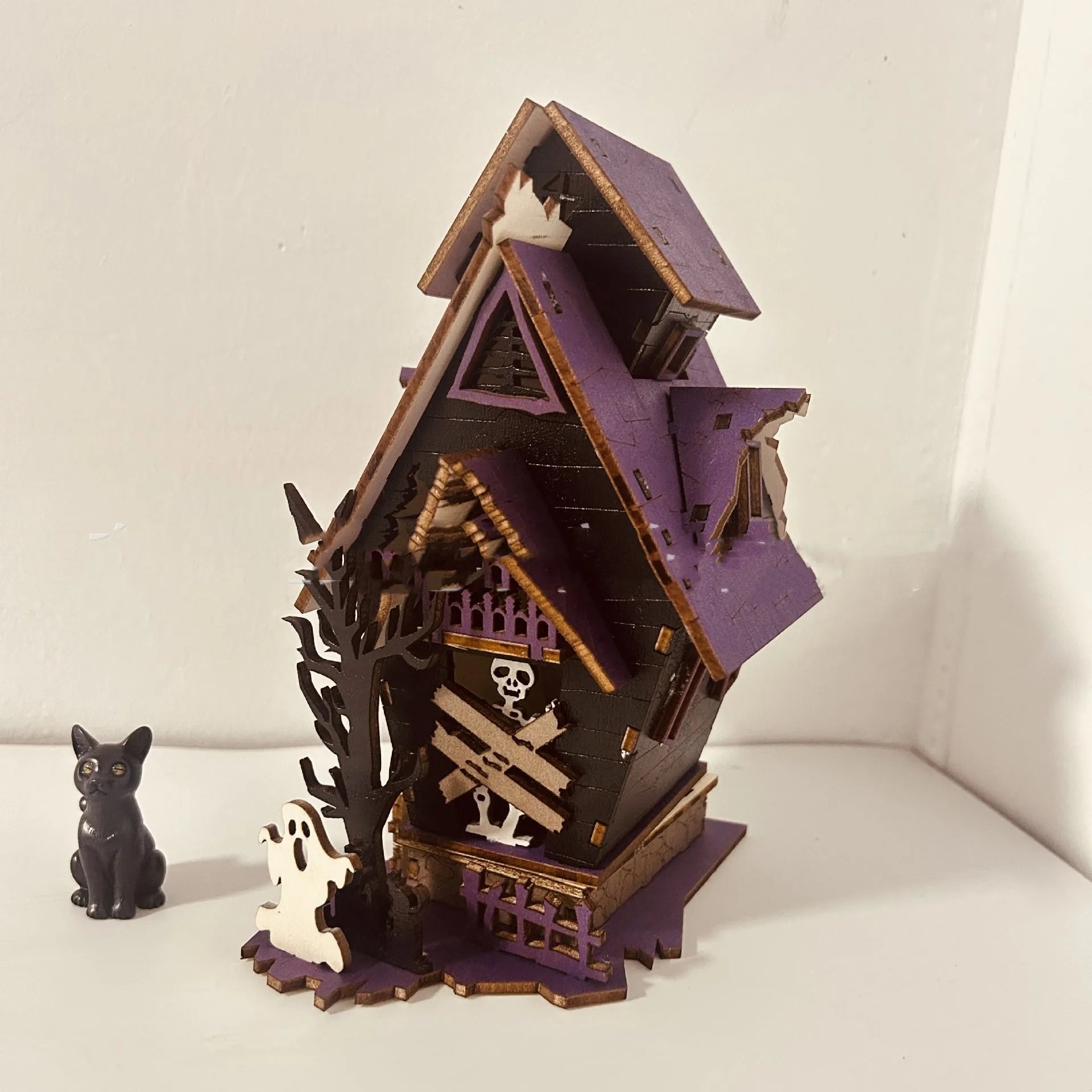 Unpainted DIY wooden haunted house Halloween decoration for use as a candlestick, shown next to a ruler for scale.