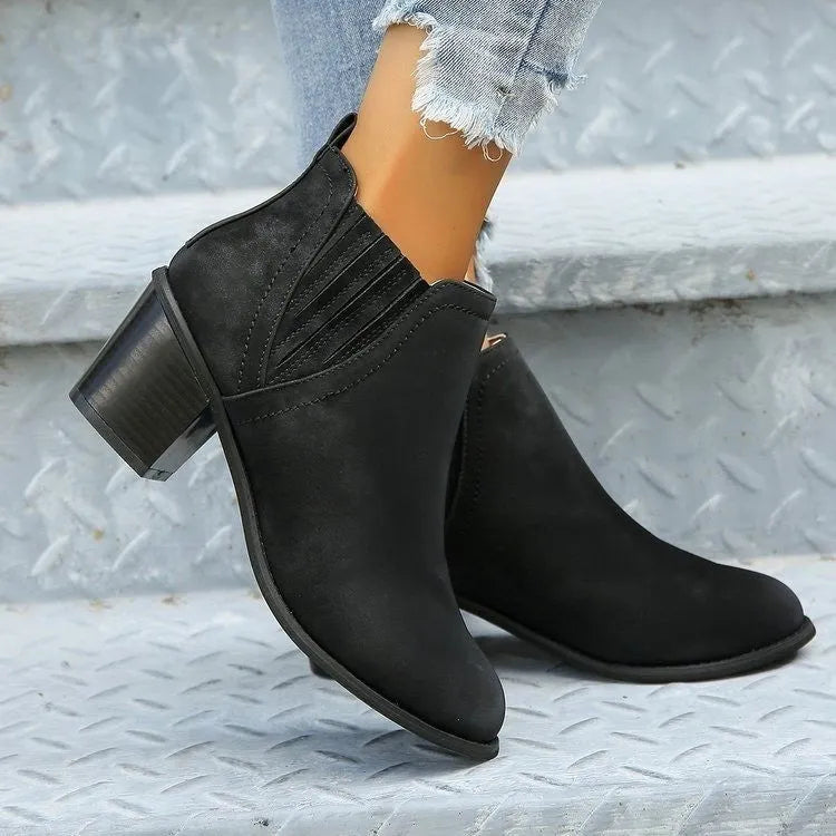 Women's black pointed toe ankle boots with thick square low heel on wooden floor