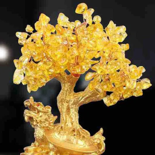 Citrine coloured resin small water turtle money tree Feng Shui ornament on a surface.