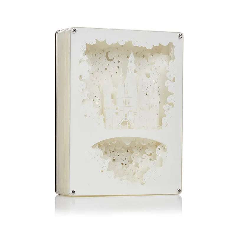 Modern three-dimensional paper carving night light with USB cable and remote control on a bedside table.