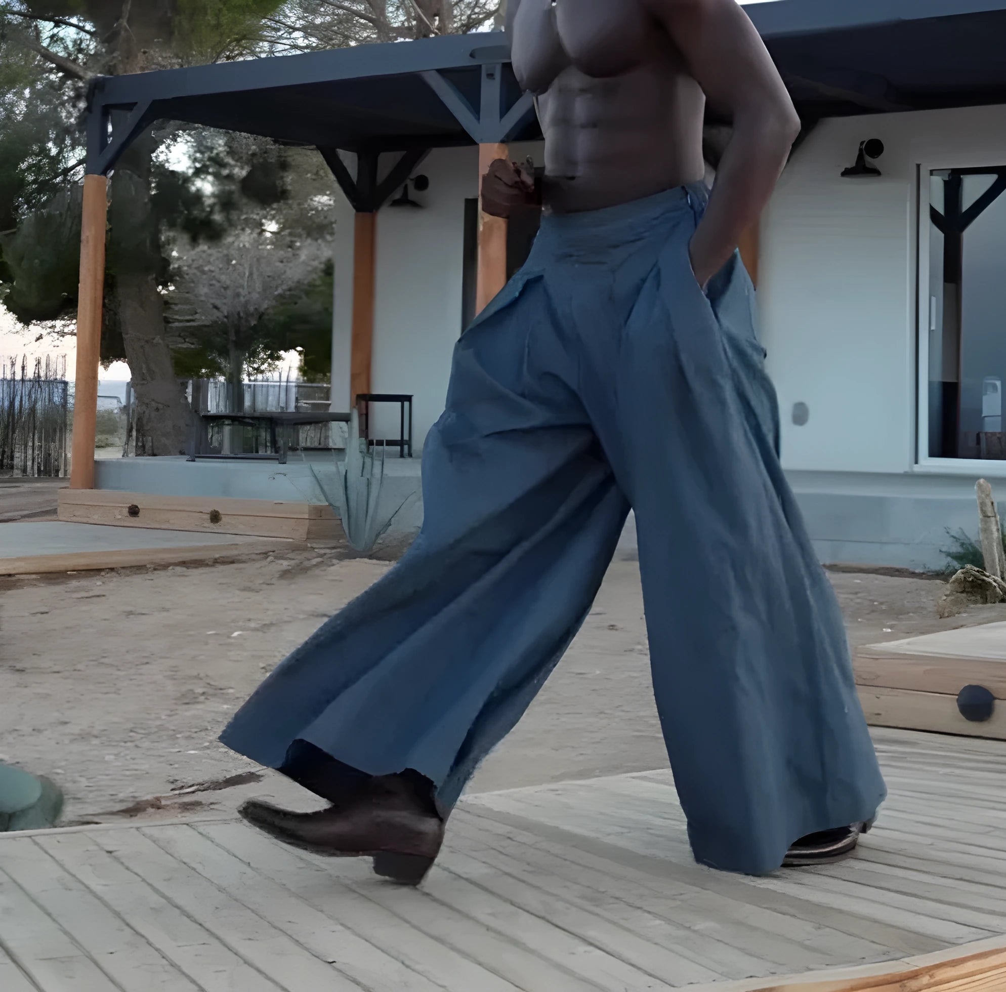 Men's grey pleated wide-leg trousers with an elasticated waistband laid flat.