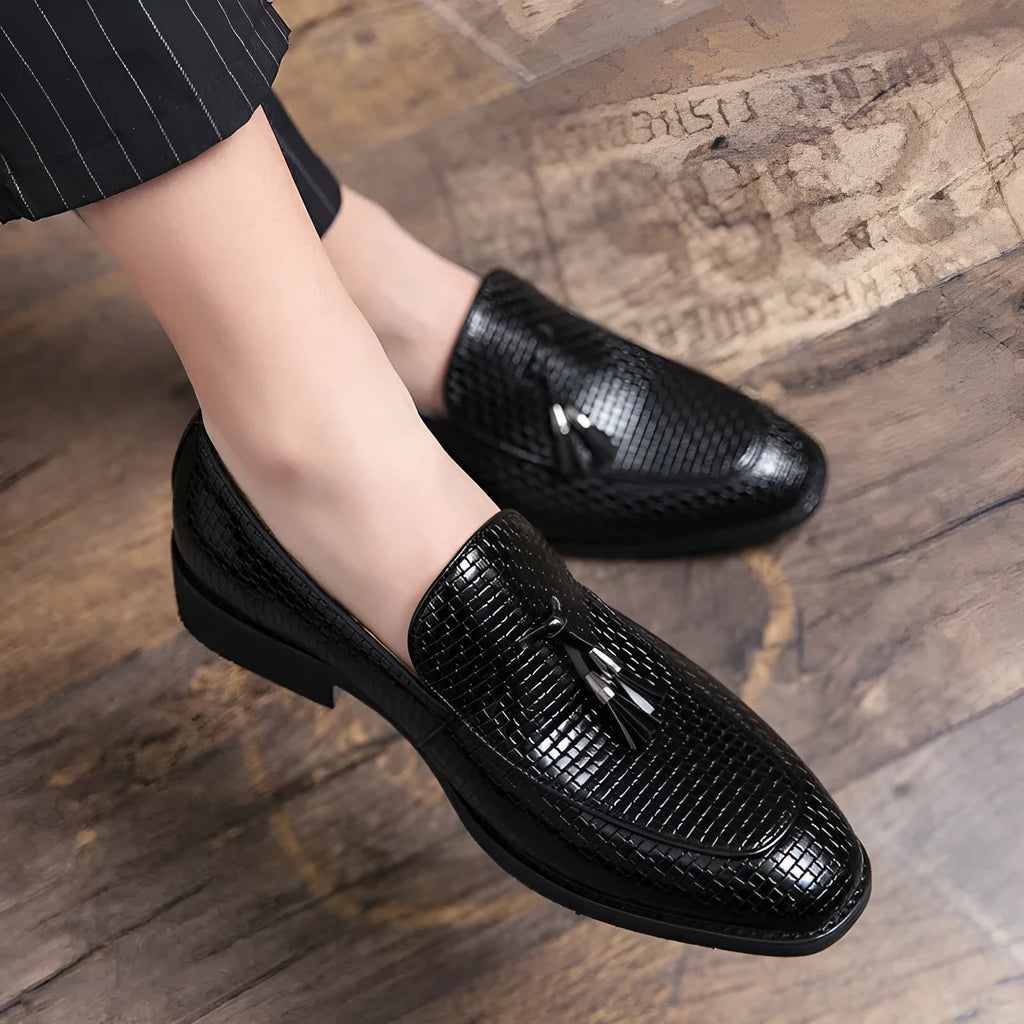 Men's black pointed-toe slip-on shoes with a tassel detail on the low-top PU upper.