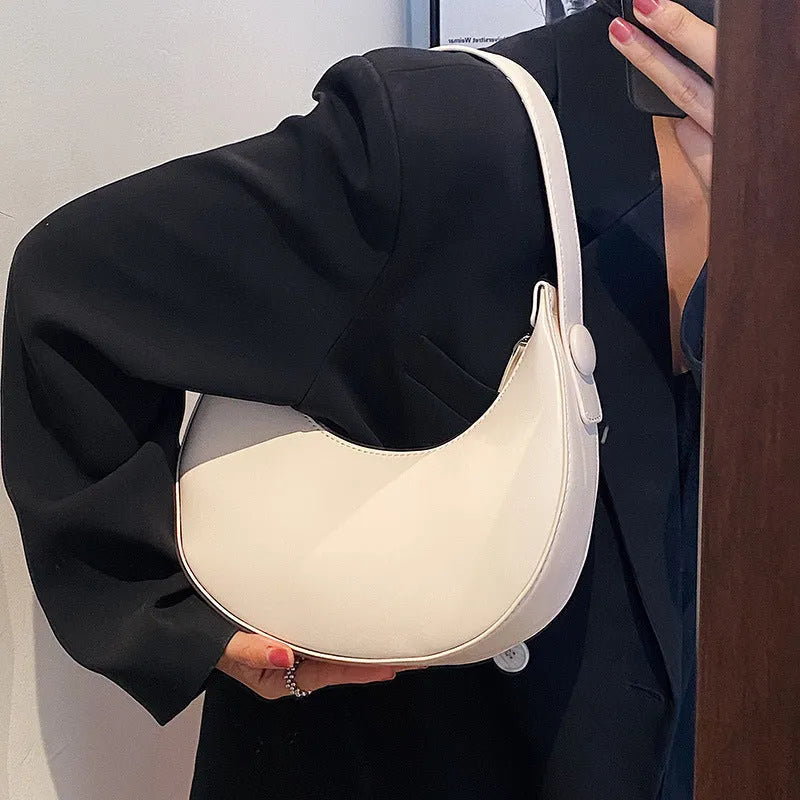 Women's retro-style PU dumpling shoulder bag in black, showing front zipper compartment.