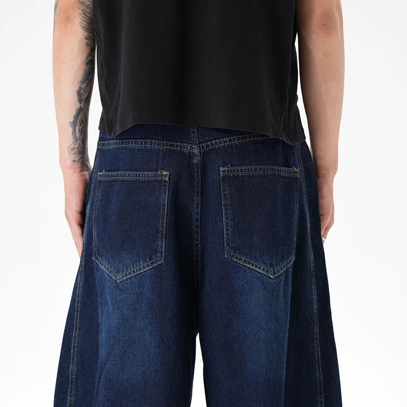 Dark blue distressed wide leg jeans with a machete cut design on a denim fabric.