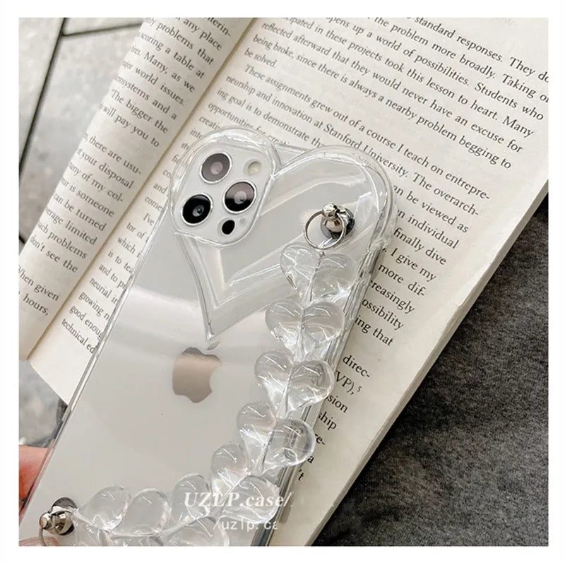 Transparent iPhone case with a love heart charm on a chain, on an iPhone.