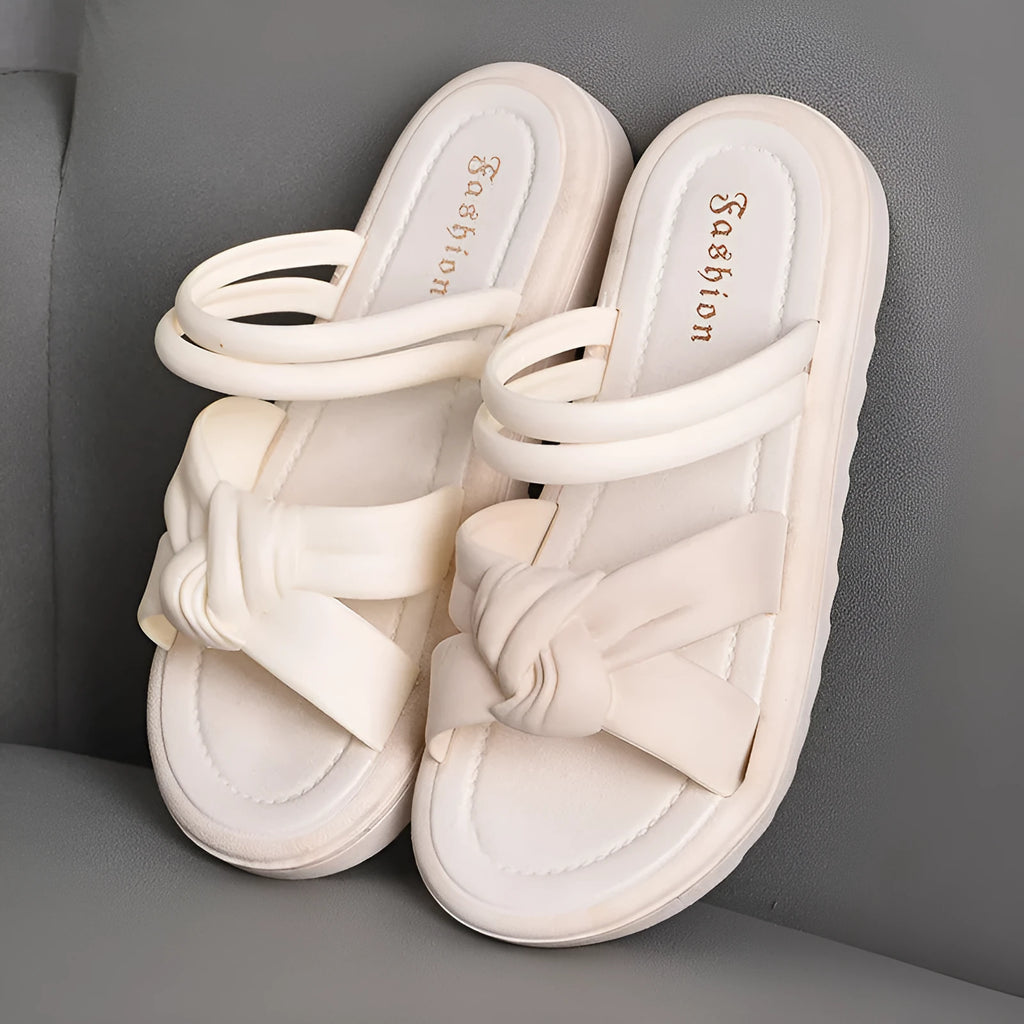 Women's black PVC sandals with soft back, floral detail, and a thick height-increasing sole.