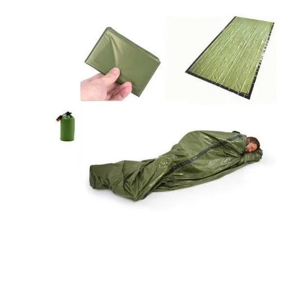 Orange aluminium foil emergency sleeping bag with drawstring bag and whistle on ground