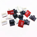 Black and white self-adhesive plastic buckle clamps for organising flat automotive wiring cables