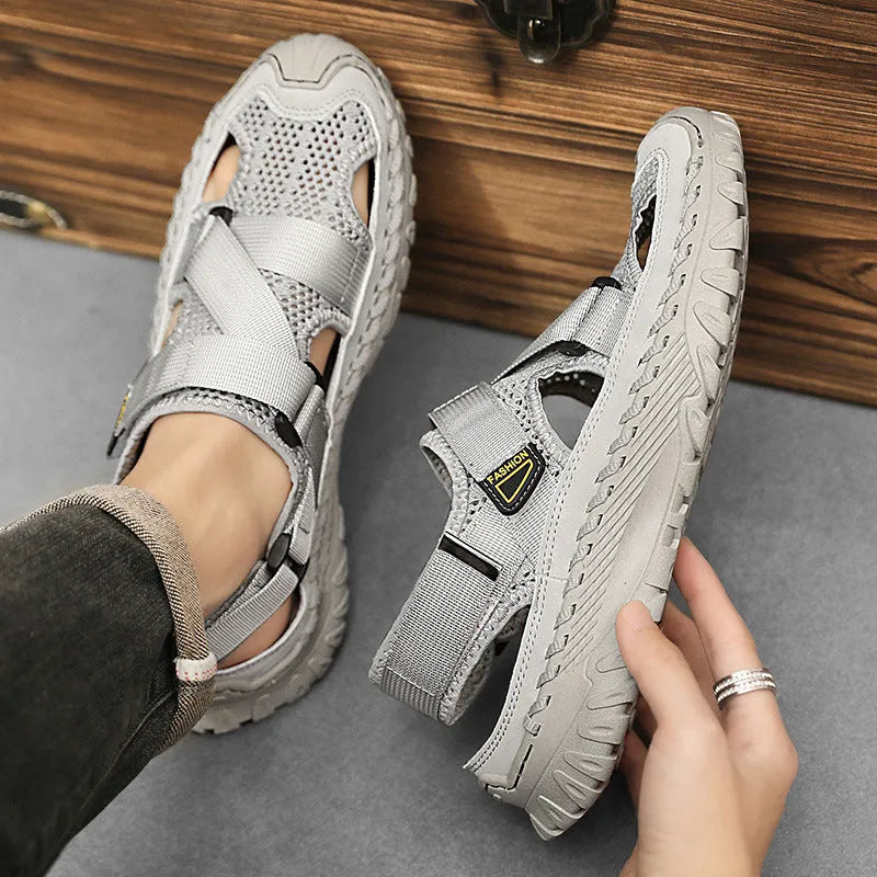 Men's grey casual sandals with a mesh lining, genuine leather upper, and an elastic band toe holder on a rubber sole.