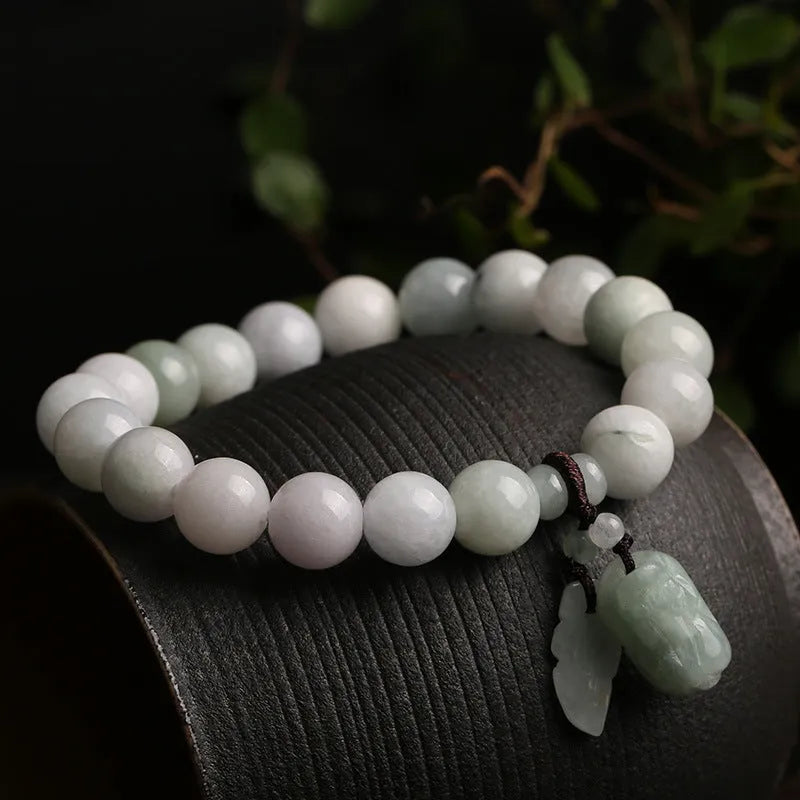 Green jade beaded bracelet with a hanging Maitreya Buddha charm on a wrist.