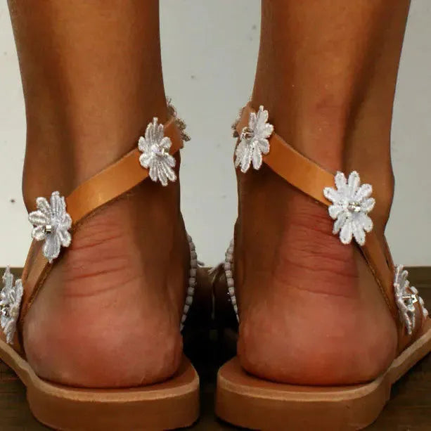 Brown women's flat Roman sandals with floral decoration and herringbone toe.