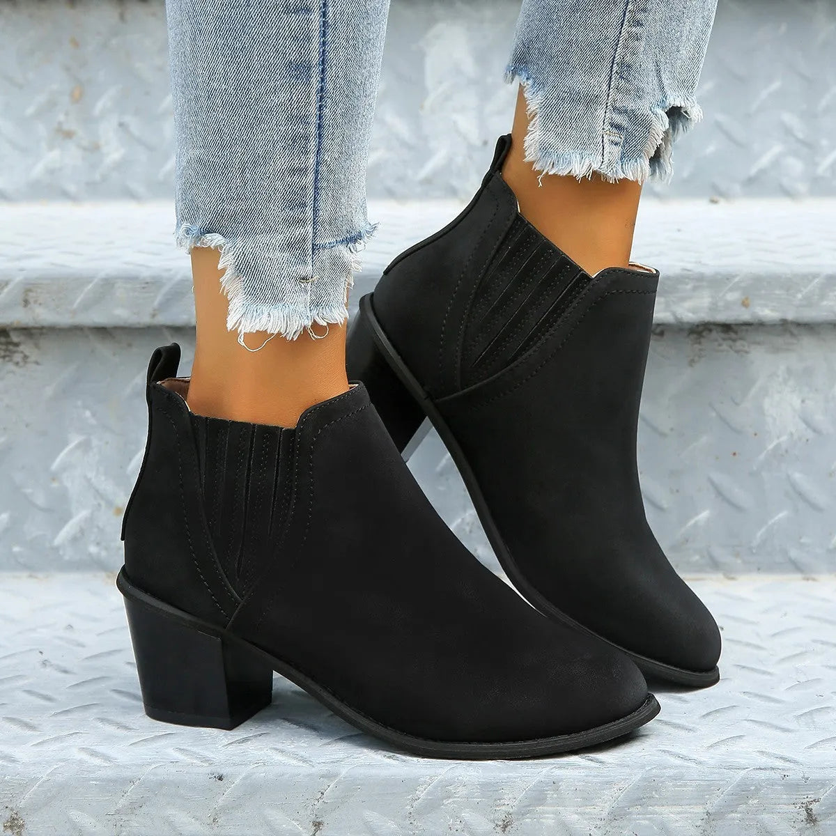 Women's black pointed toe ankle boots with thick square low heel on wooden floor