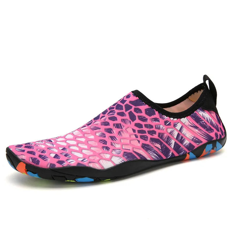 Blue and black Lycra fabric beach wading shoes with EVA foam soles on a sandy background.