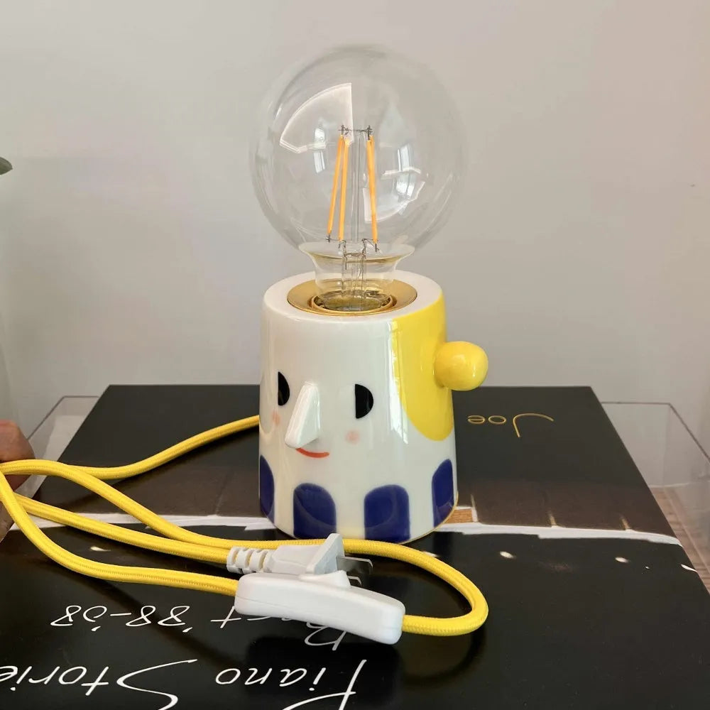 Handmade ceramic bedside lamp with a ball headlight design on a nightstand.