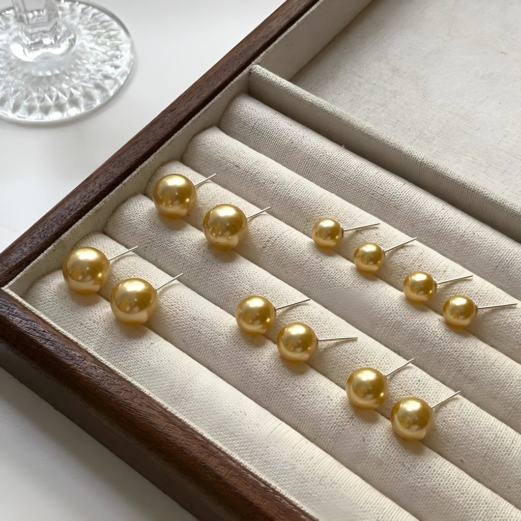 A pair of large geometric silver stud earrings with a central pearl and an eight-point star design detail.