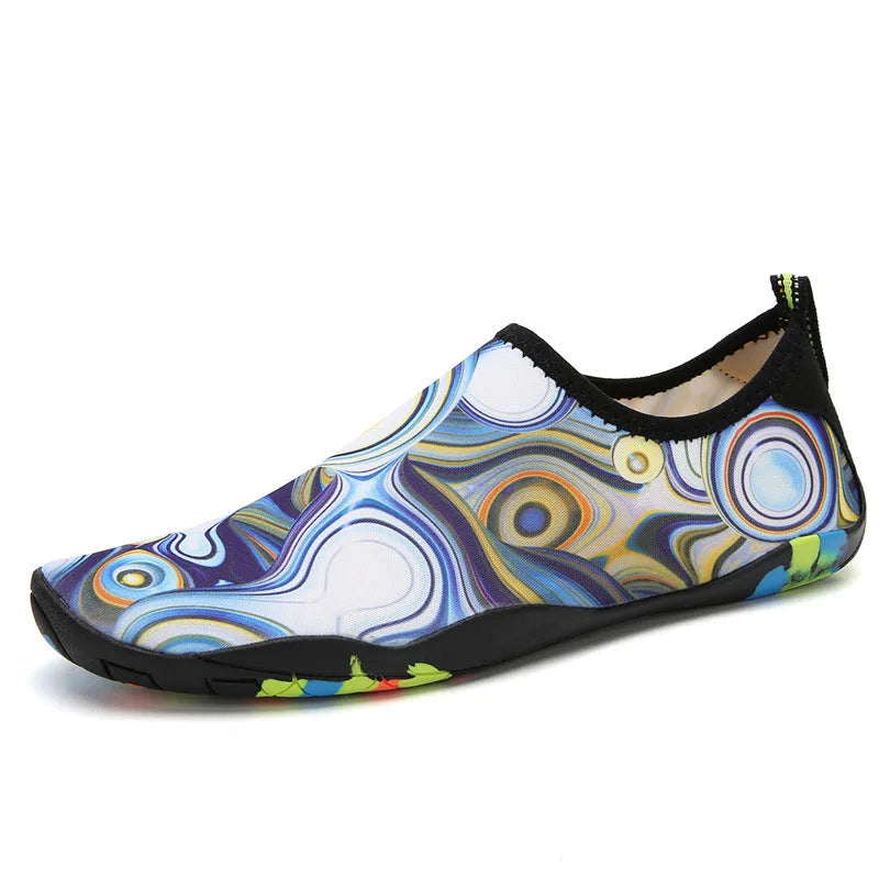 Blue and black Lycra fabric beach wading shoes with EVA foam soles on a sandy background.
