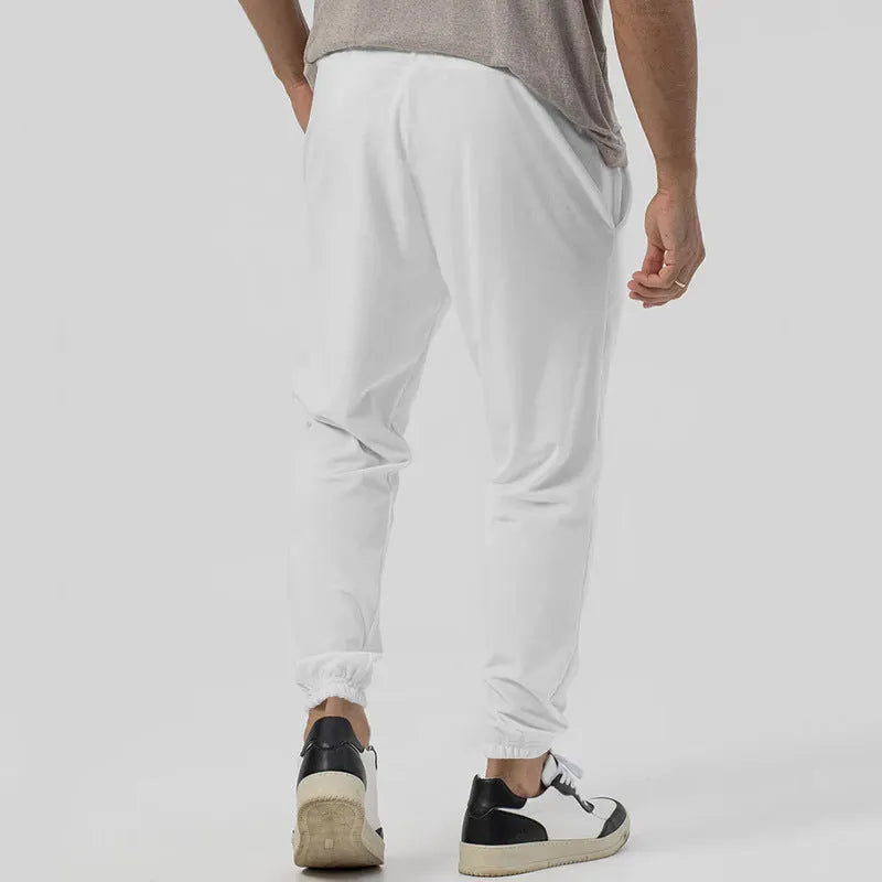 Men's grey loose tapered track sweatpants on a hanger, showing straight-leg design.