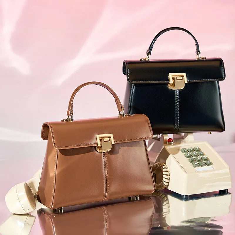 Women's black leather shoulder bag with vachette clasp showing interior zippered compartments