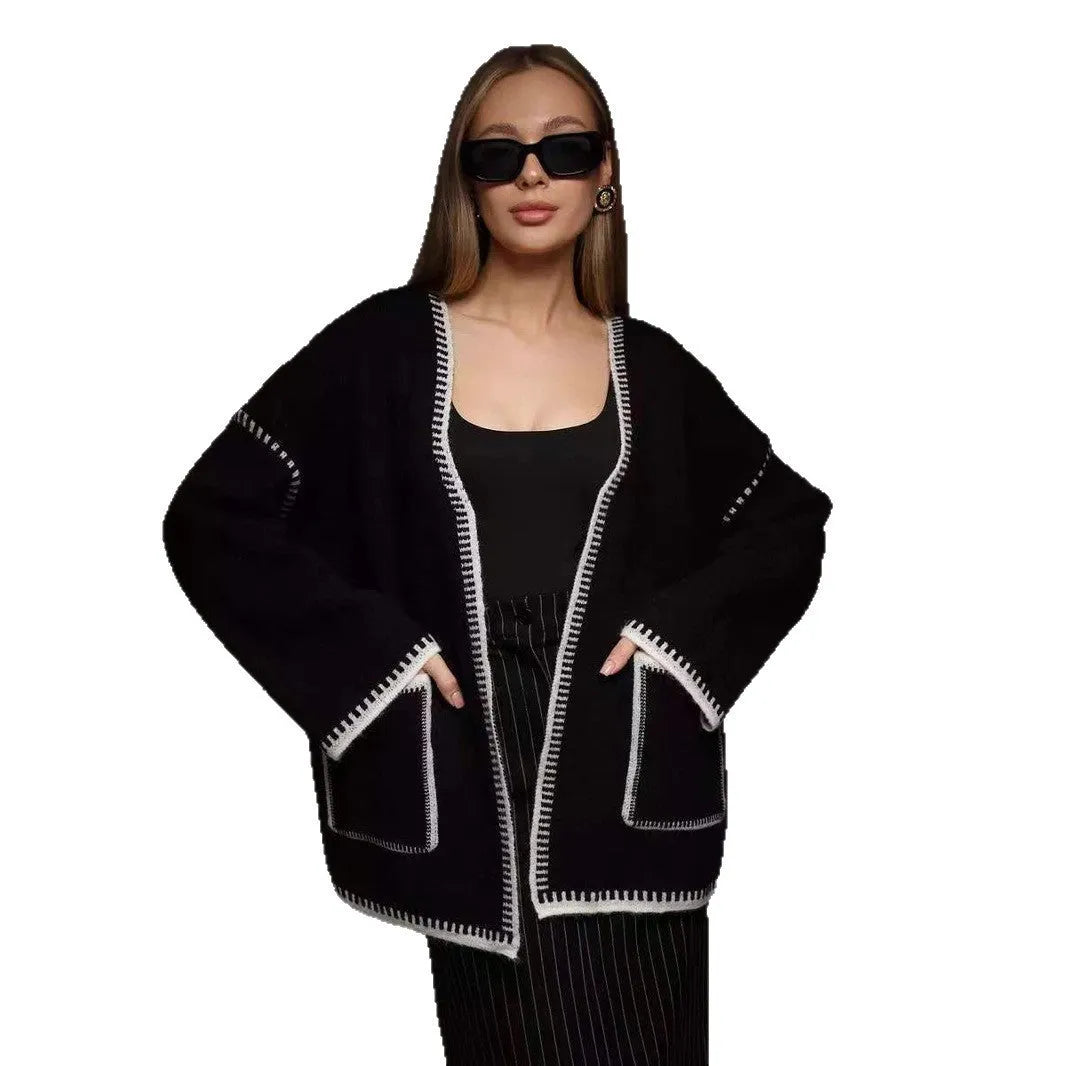 A white lace-up knitted cardigan with long sleeves on a hanger, showing the front tie detail.