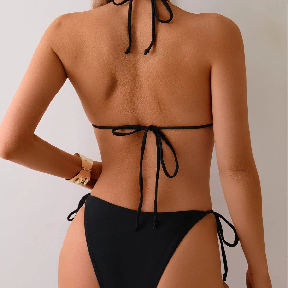 Black women's bikini swimsuit with metal bead decoration and a split design.