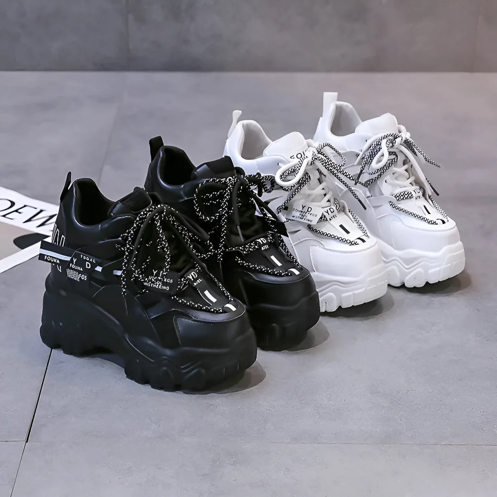White and black women's low-top platform sports shoes with a cross strap and mesh upper.