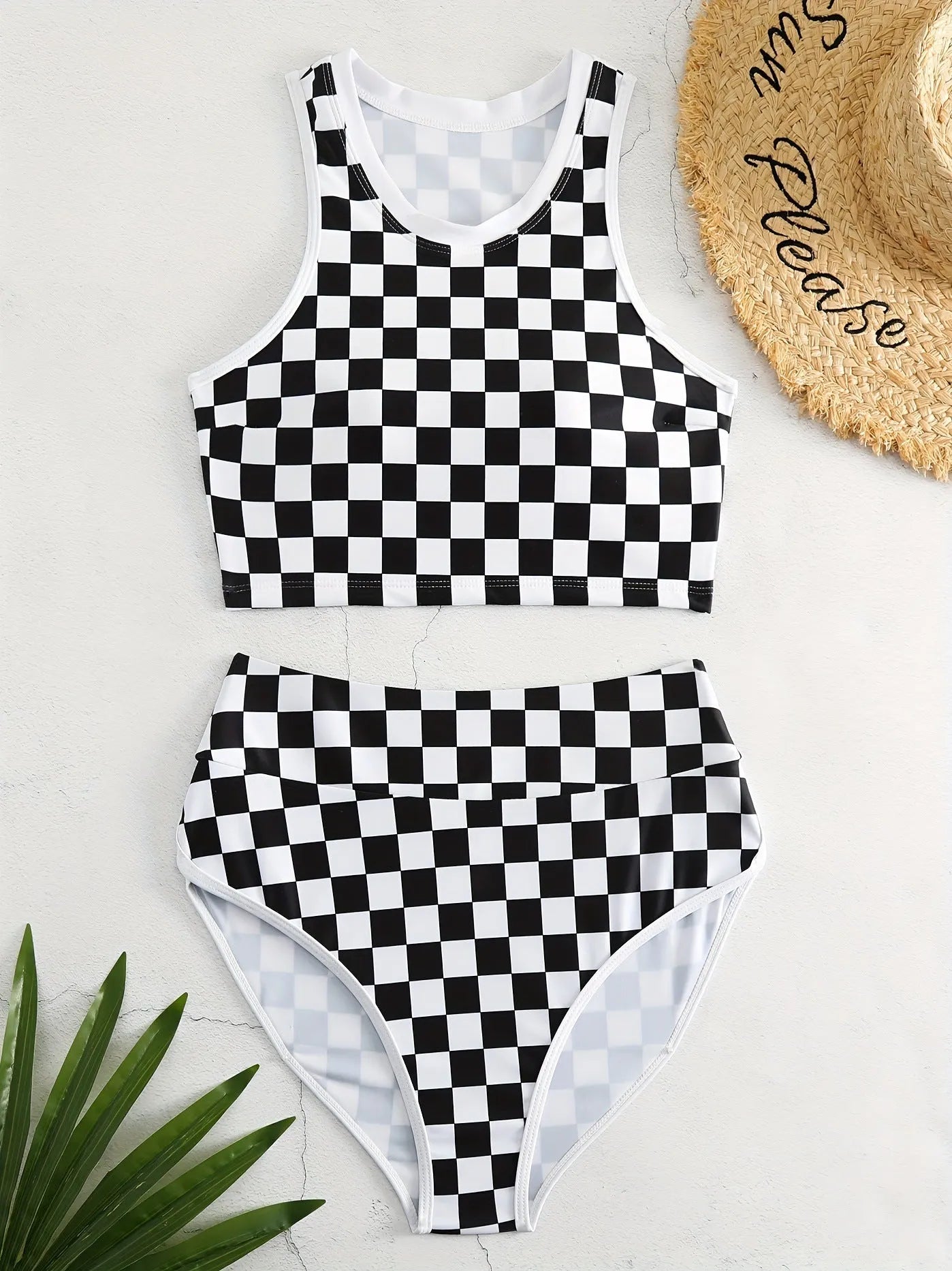 Backless one-piece women's swimsuit with black and white chessboard plaid pattern and white suspender straps.