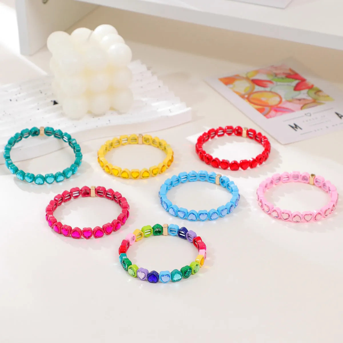 Colourful enamel finish alloy heart charm on a black stretch bracelet band.