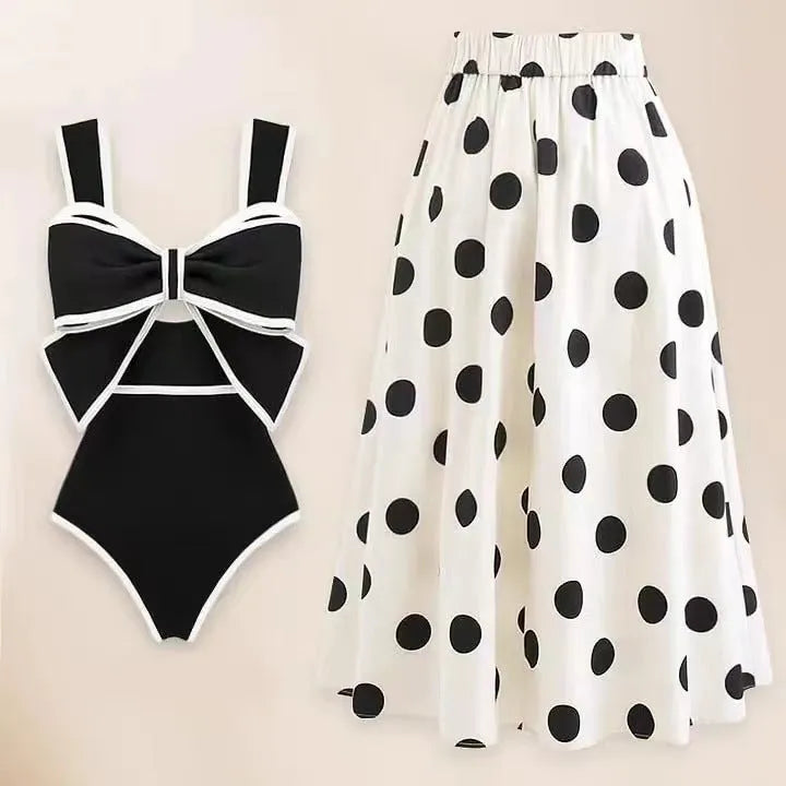 Women's black one-piece swimsuit with white skirt and bow detail on front.