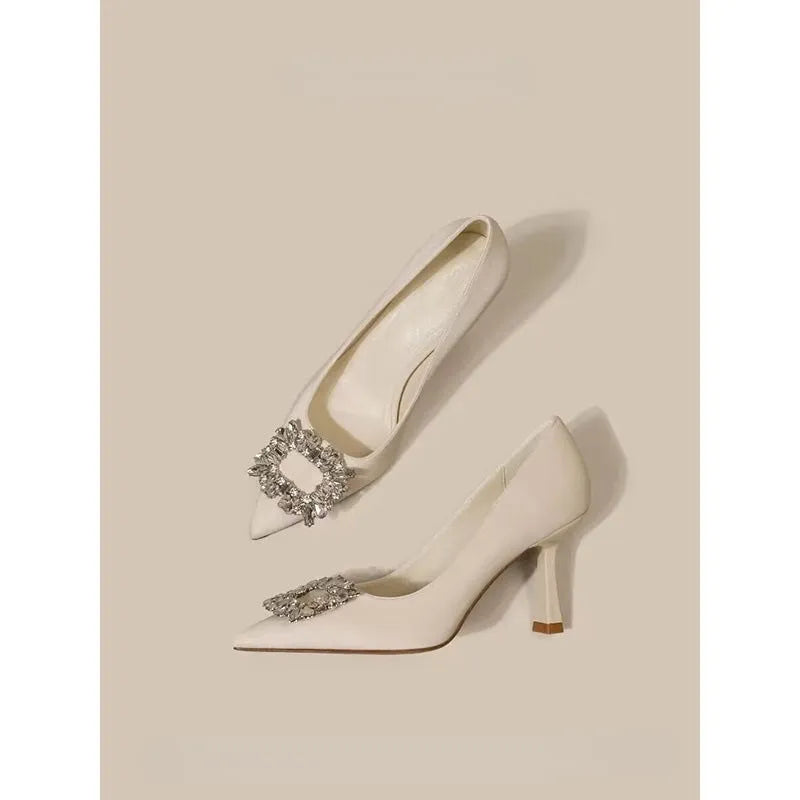Women's creamy-white pointed toe stiletto pumps with a mid-height heel on a plain background.