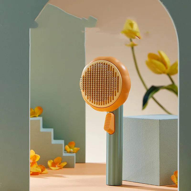 Hand holding a white and pumpkin coloured pet grooming brush with many stainless steel needles.