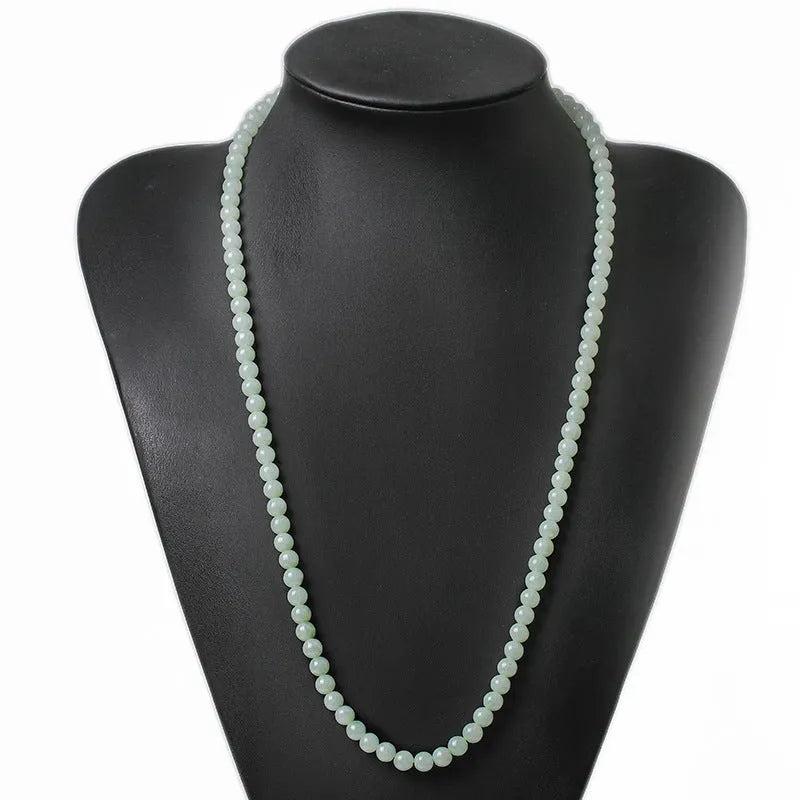 Close-up of a women's adjustable necklace with round white and green natural jade beads on a metal chain.