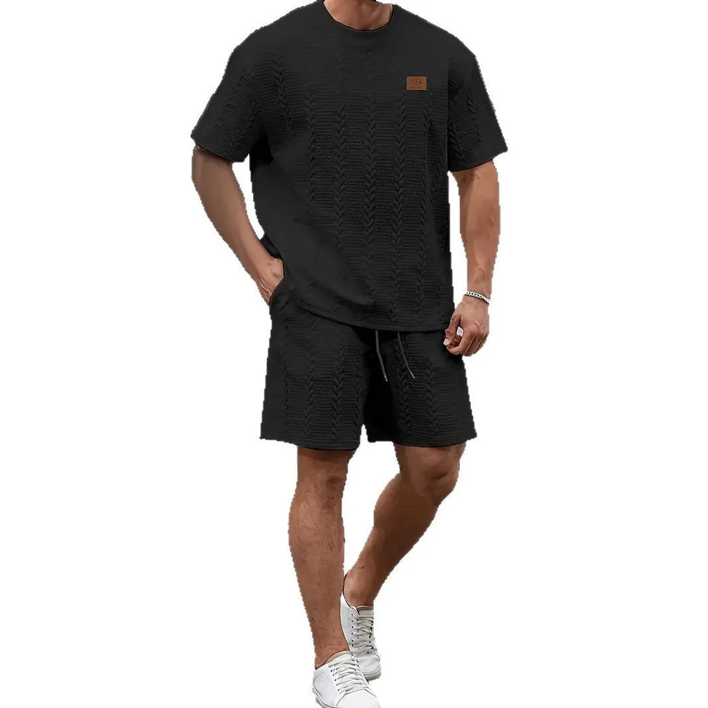 Men's black ribbed two-piece sports set with patch design on short sleeve top and matching shorts