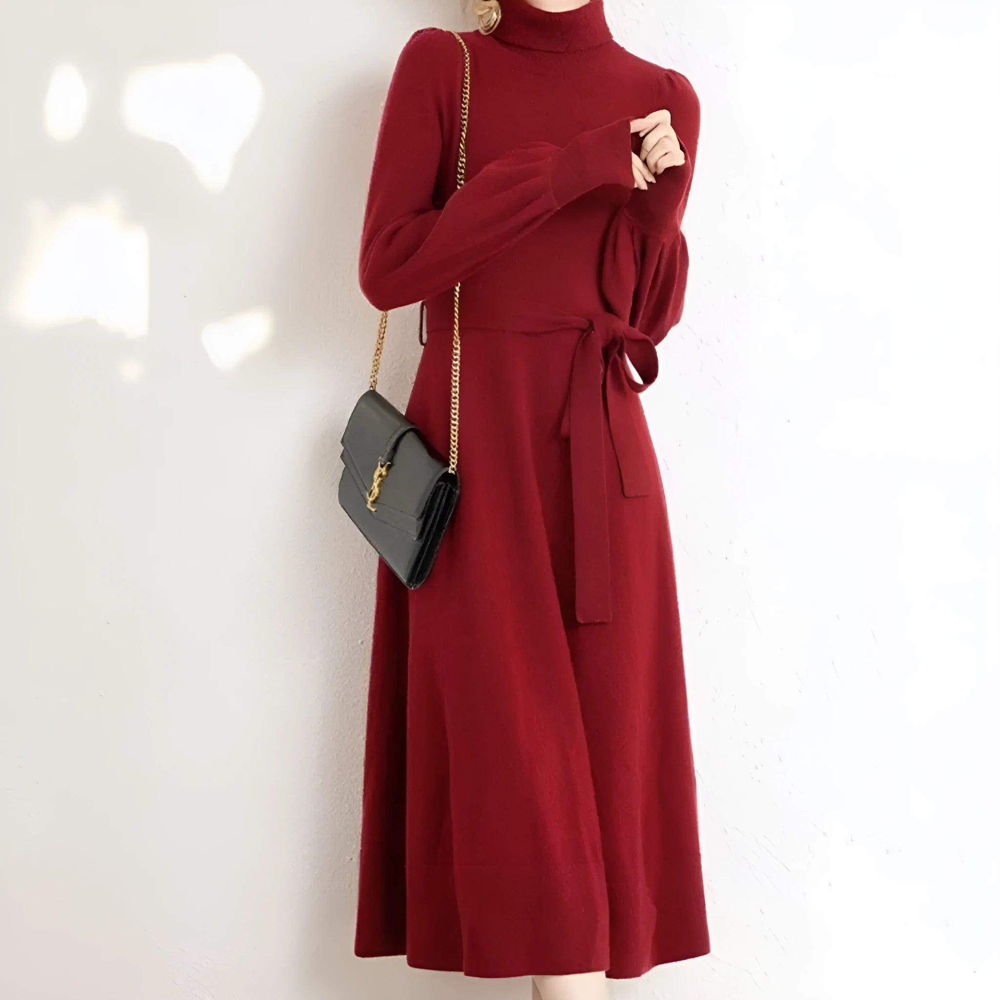 A woman wearing a rose red turtleneck long sleeve knitted dress with an elastic waist and a loose mid-length skirt.