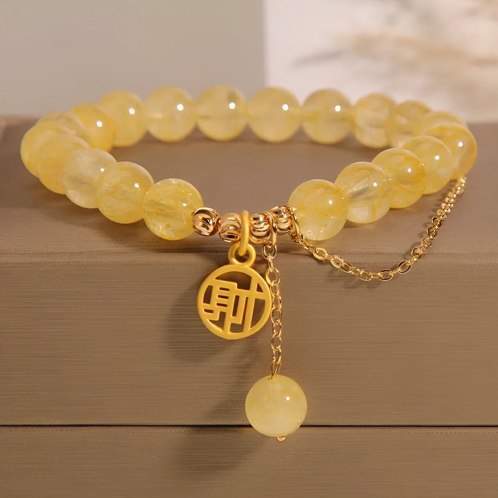 Women's natural citrine bracelet with a gold-tone Chinese character charm and tassel on an adjustable chain.