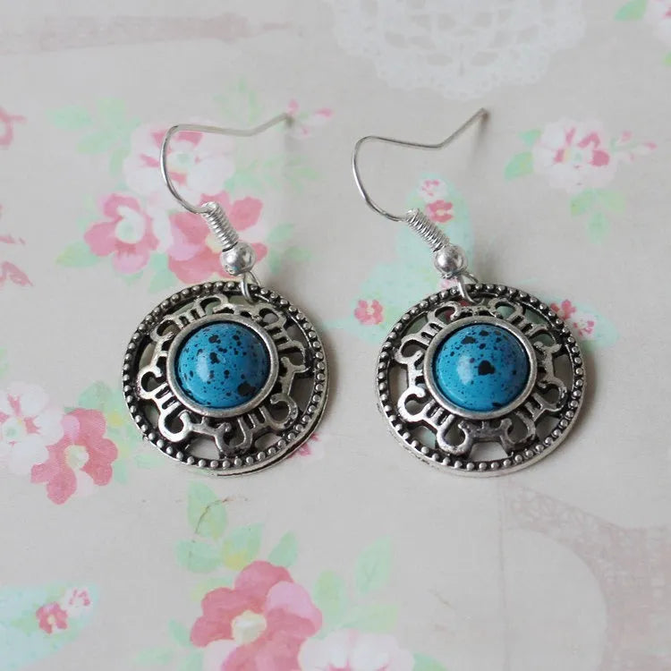 Handmade Miao ethnic style silver earrings with a blue turquoise flower disk and geometric patterns.