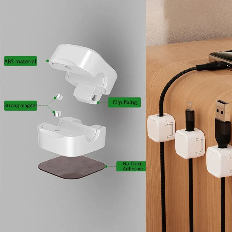 White and black magnetic cable clips with adhesive backing holding a USB cable against a wooden desk edge.