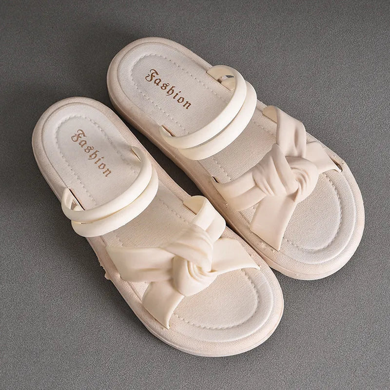 Women's black PVC sandals with soft back, floral detail, and a thick height-increasing sole.