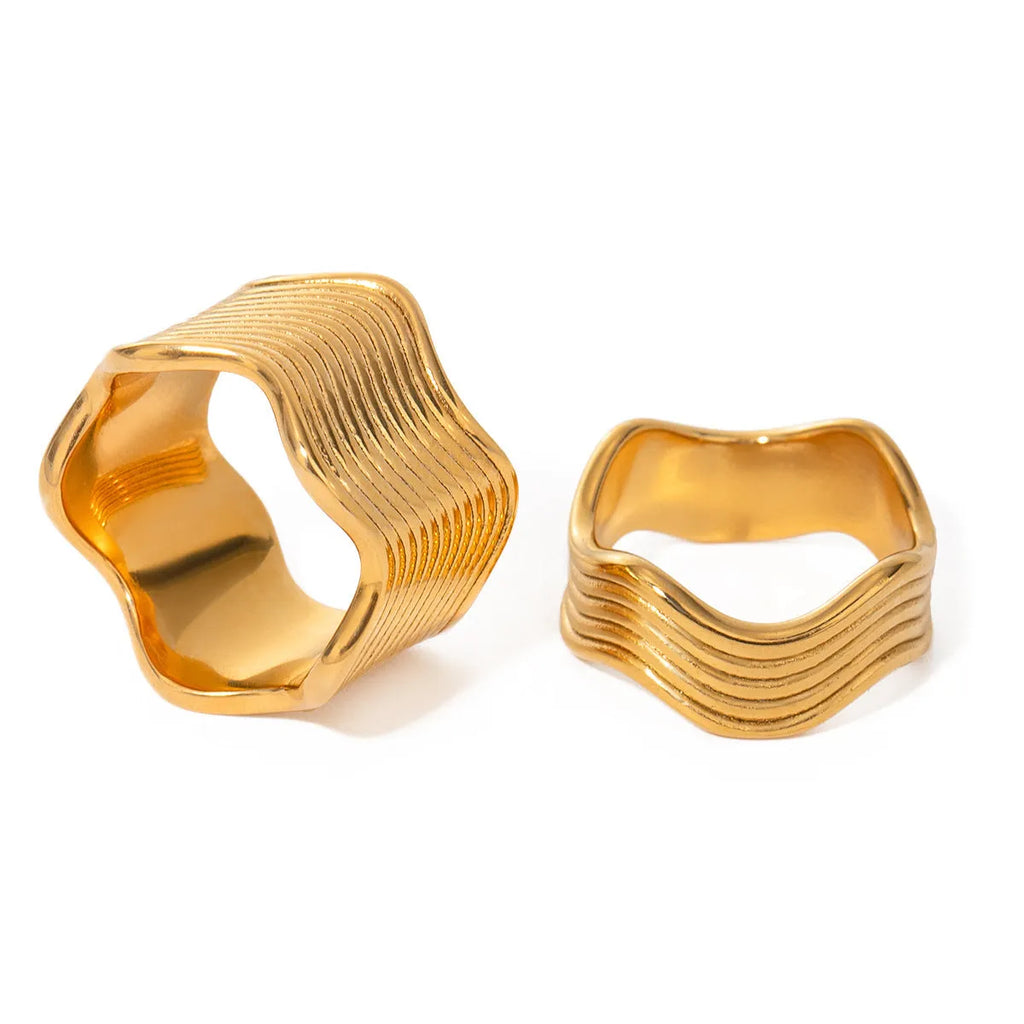 Close-up of a wide stainless steel ring with a geometric wave texture, shown in a silver tone finish.